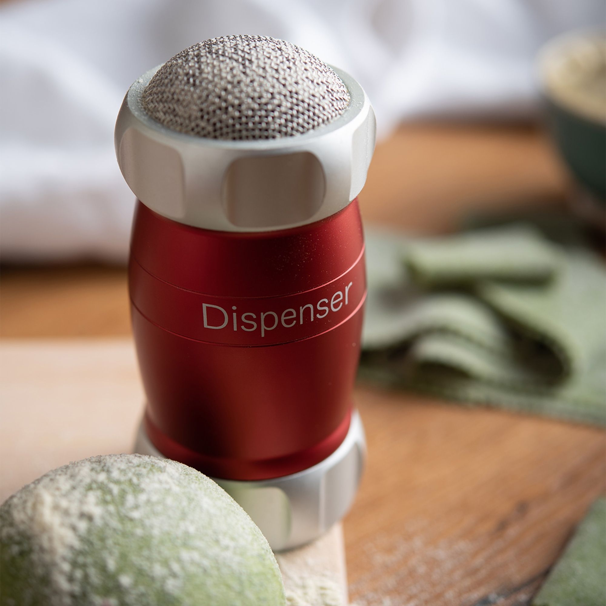 Red flour dispenser on wooden worktop